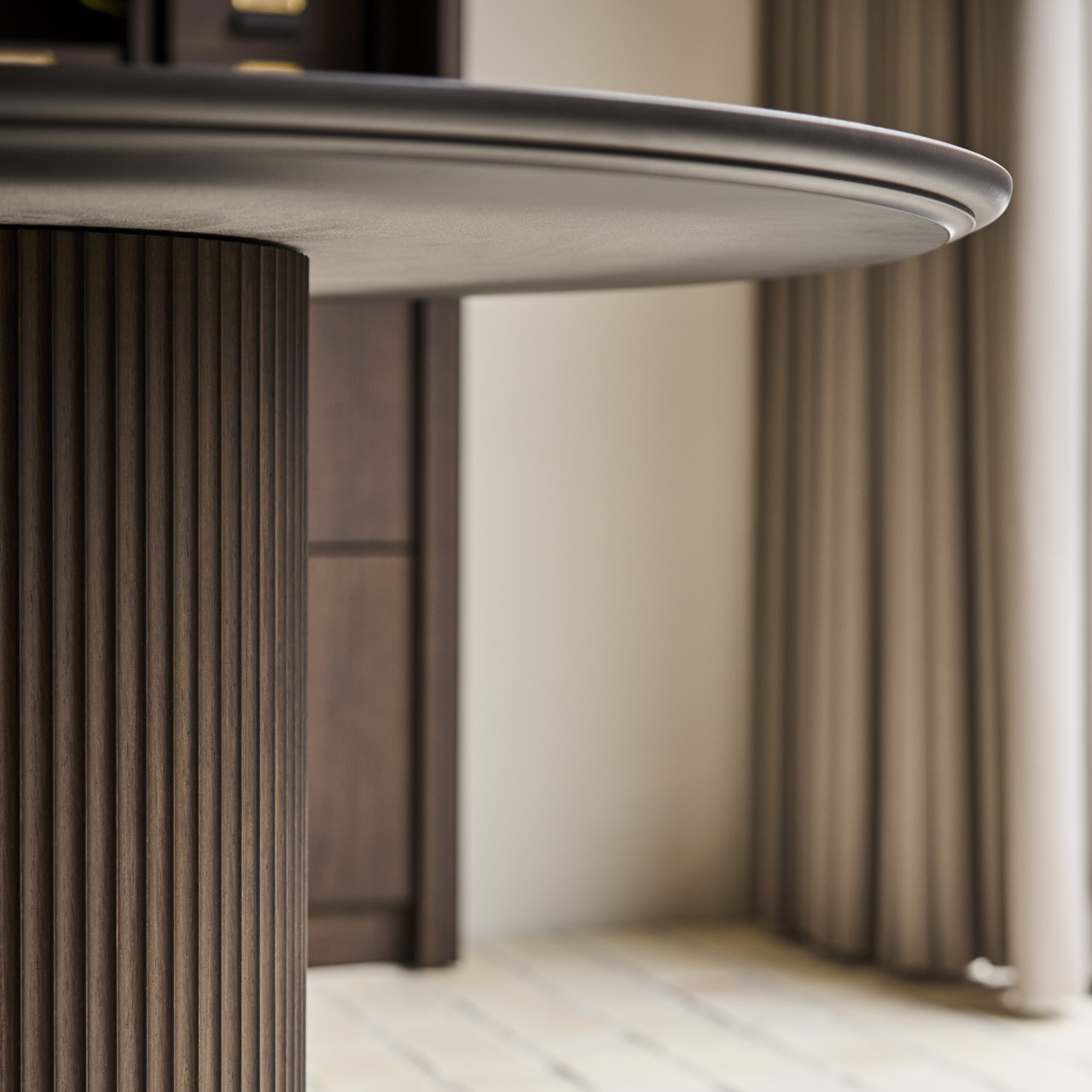 Close-up of a modern table with a cylindrical base on a light wooden floor.