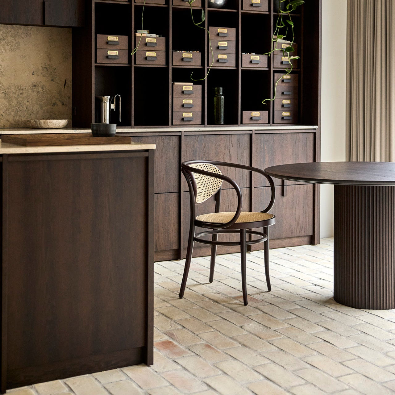 Modern kitchen with dark wood cabinetry and round dining table.